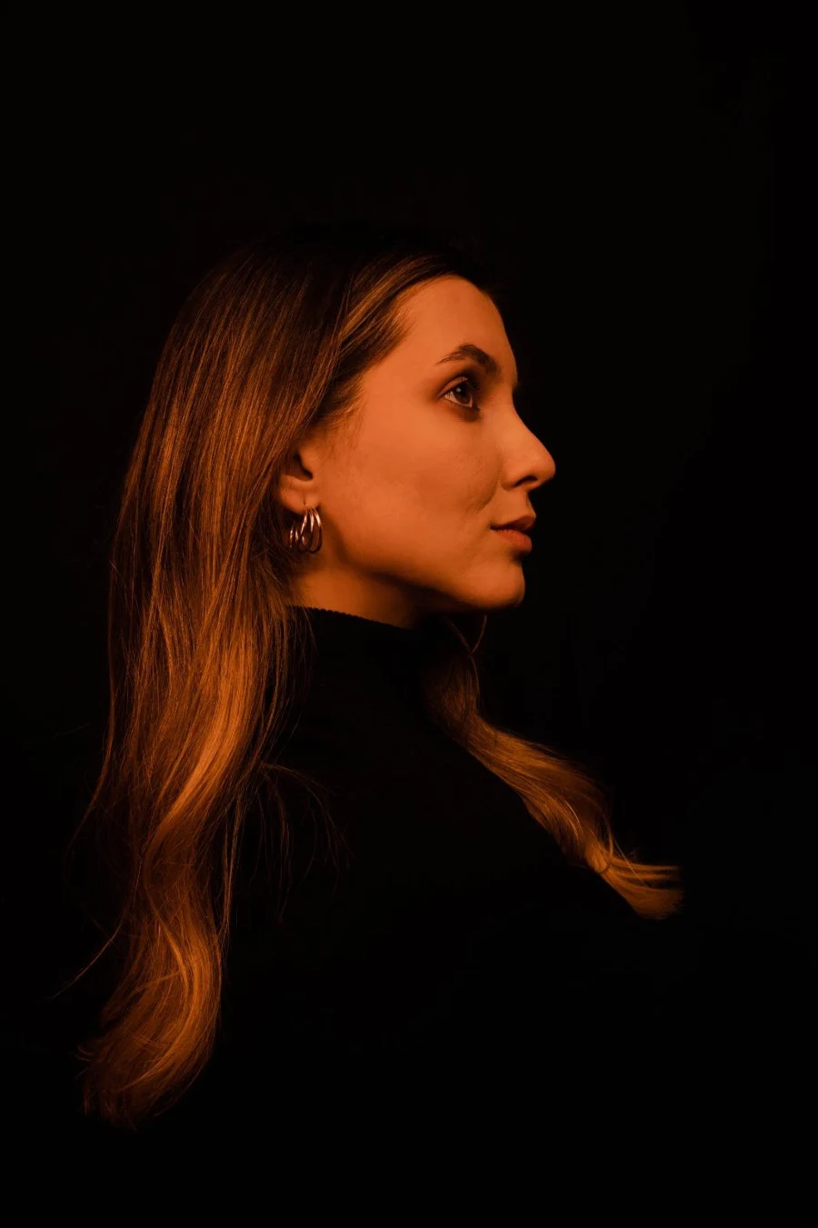 Sorina in profile, lit in warm amber against a dark background